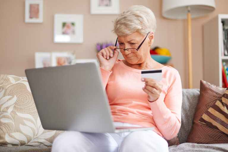 Donna anziana che acquista su internet con la carta. Accede a servizi essenziali